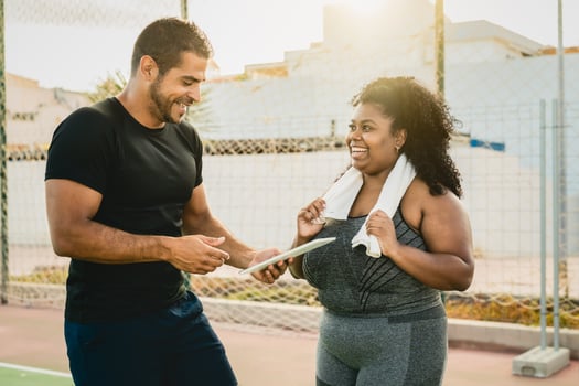 Personal trainer working with curvy woman while giving her istruction with digital tablet during training session - Sport people lifestyle concept photo
