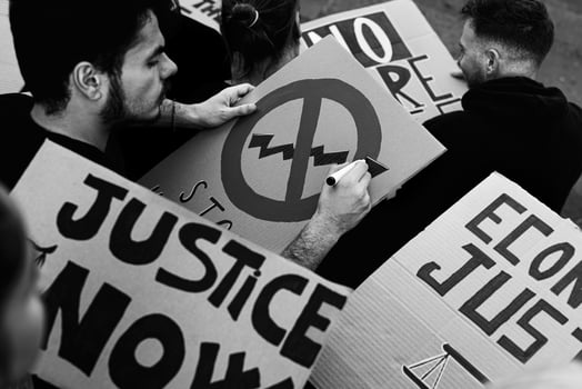 Multiracial activists preparing protest signs against banks financial crisis and global inflation - Activism and economic justice concept - Black and white editing photo
