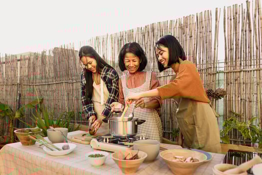Southeast asian mother with her daughters having fun preparing food recipe together at house patio photo