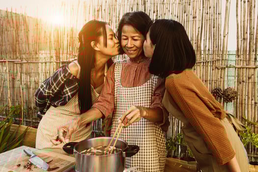 Southeast asian mother with her daughters having fun preparing Thai food recipe together at house patio photo