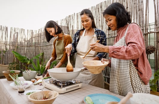 Southeast asian mother with her daughters having fun preparing Thai food recipe together at house patio photo