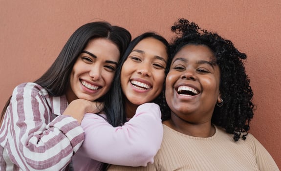 Portrait of happy multiracial friends embracing and smiling in front of camera photo
