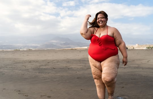 Happy plus size woman having fun walking on the beach - Curvy confident people lifestyle concept photo