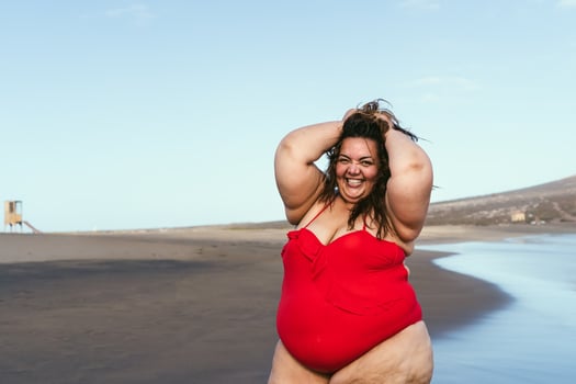 Happy plus size woman posing on the beach - Curvy overweight model having fun during vacation in tropical destination - Over size confident person concept photo