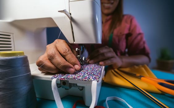 Woman working with sewing machine doing homemade medical face mask for preventing and stop corona virus spreading - Textile seamstress and healthcare concept photo