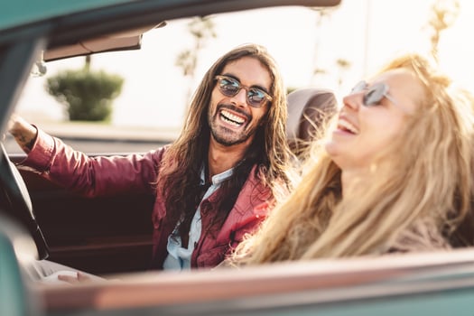 Happy young couple doing road trip in tropical city - Travel people having fun driving in trendy convertible car discovering new places - Relationship and youth vacation lifestyle concept photo