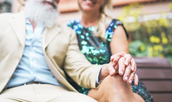 Happy senior couple having a romantic moment outdoor - Mature elegant people spending time together sitting on bench - Love, affection and elderly lifestyle concept photo
