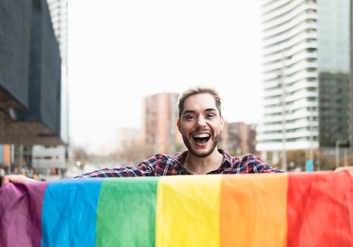 Happy gay man having fun holding rainbow flag symbol of LGBTQ community photo
