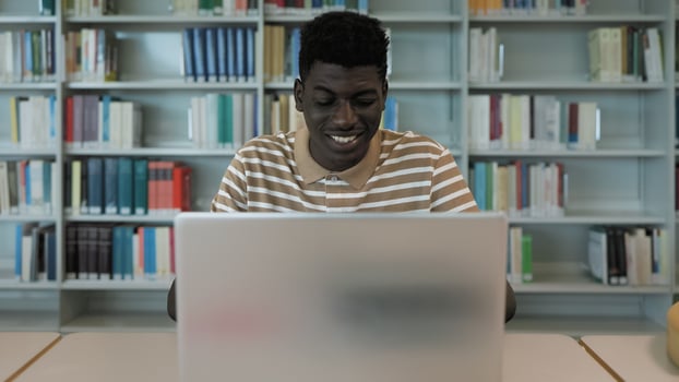 Young African student using laptop in library - School education concept photo