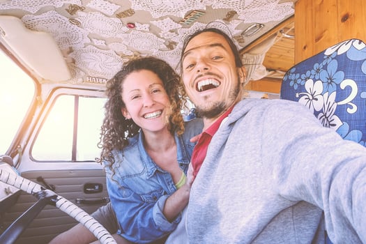 Happy couple taking a selfie inside a vintage minivan - Travel people excited and ready for driving to road trip with a van camper - Vacation, love, relationship lifestyle concept photo