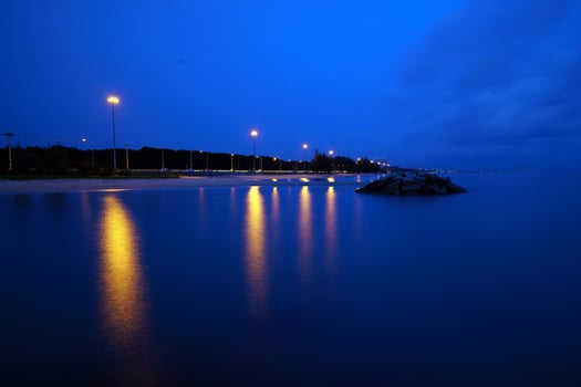The road follows the coast at dusk and is lit by light poles photo