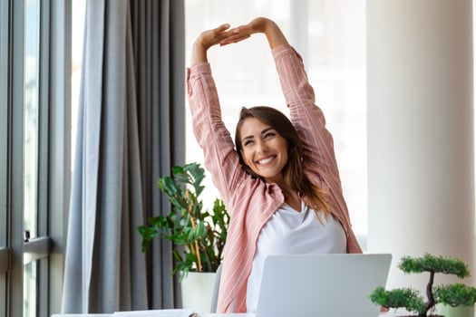 Young woman working on laptop. Business woman busy working on laptop streching. Businesswoman sitting at bright modern work station photo