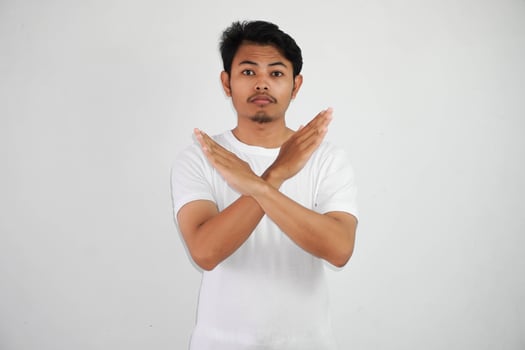 serious young Asian man wearing white t shirt show cross arms for disagree say no isolated on white background photo