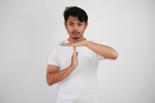 serious young asian man giving time out hand gesture wearing white t shirt isolated on white background photo