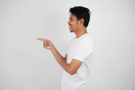 smiling asian man with fingers pointing to the side wearing white t shirt isolated on white background photo