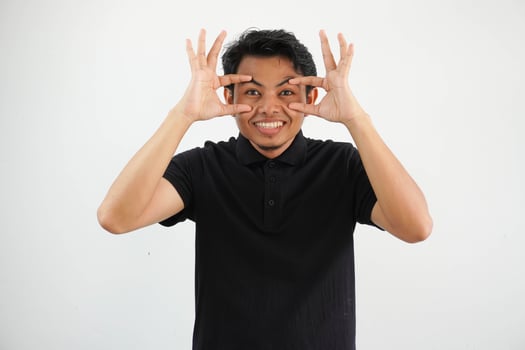 young asian man posing keeping eyes opened to find a success opportunity, wearing black polo t shirt isolated on white background photo
