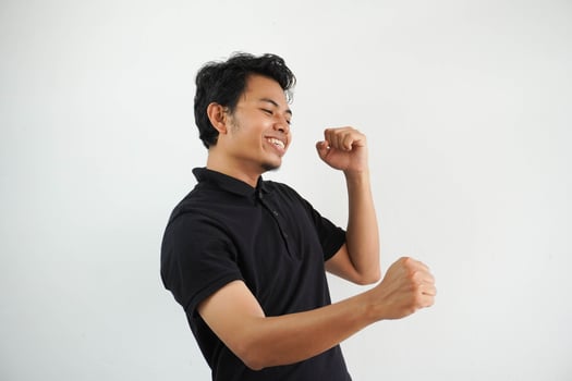 happy young asian man dancing and having fun wearing black polo t shirt isolated on white background photo