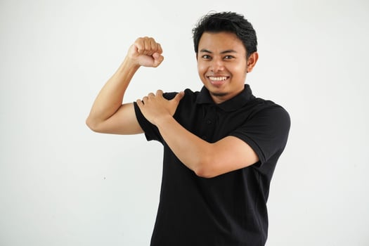 young asian man against a vibrant white studio background, showing strength gesture with arms, symbol of power wearing black polo t shirt. photo