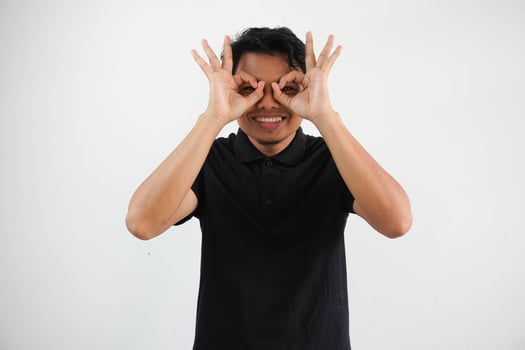 young asian man excited keeping ok gesture on eye, wearing black polo t shirt isolated on white background photo