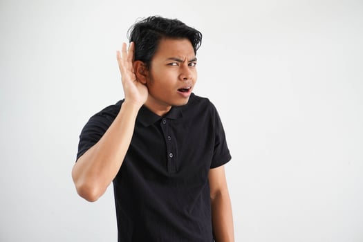 young Asian man looking camera and doing can not hear gesture, trying to listening a gossip wearing black polo t shirt isolated on white background photo
