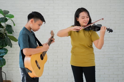 Asian boy playing guitar and mother playing violin, feel appreciated and encouraged. Concept of a happy family, learning and fun lifestyle, love family ties photo