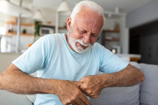 Elderly man has pain in fingers and hands. Old man with finger pain, Man massaging his arthritic hand and wrist. photo