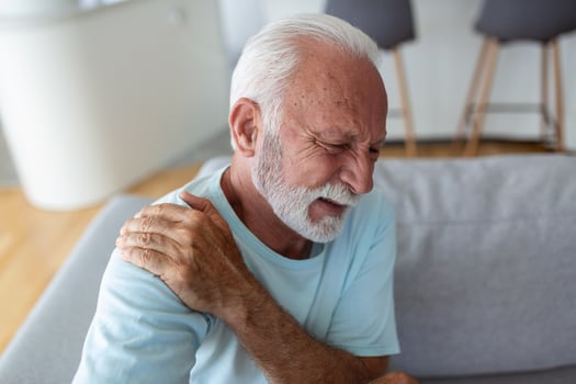 Senior elderly man touching his shoulder, suffering from shoulder pain, sciatica, sedentary lifestyle concept. shoulder health problems. Healthcare, insurance photo
