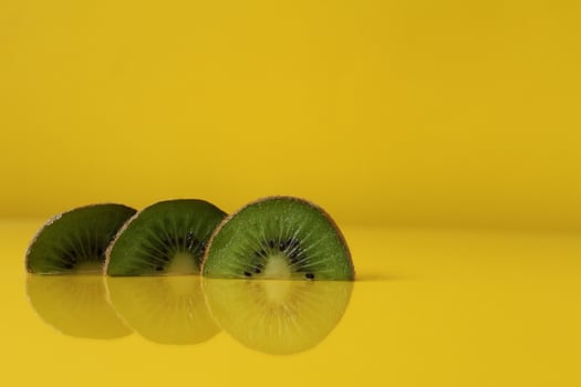 Three slices of kiwi halves lie in a row on trend iluminaited yellow with a copy of the space place for text photo