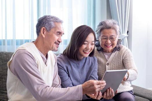 Asian family reunion of senior father, mother and daughter sitting on couch with happy smile in retirement home while looking at old nostalgic photo in the past
