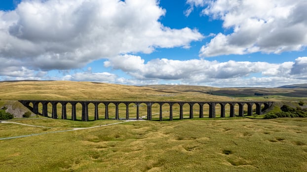 Scenic view of an old viaduct in a lush green landscape under a cloudy sky. photo