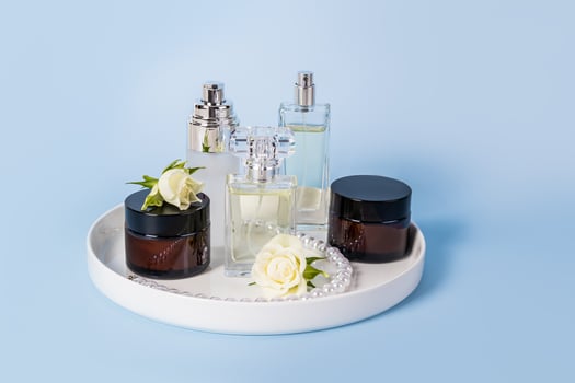 Set of natural organic facial skin care products in various jars and perfume on ceramic white tray and blue background. Perfume and beauty concept. photo