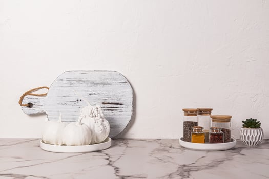 Decorative white pumpkins on a plate and jars of spices on a marble countertop. Stylish kitchen background. minimalism. A copy space. photo