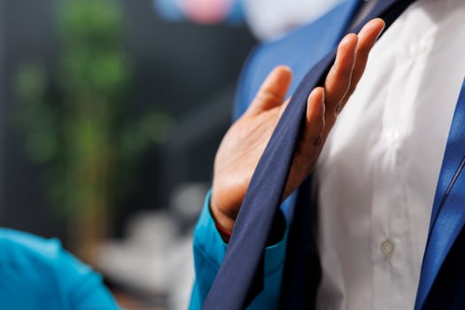 Woman holding stylish tie, analyzing clothes material during shopping session in modern boutique. African american customer looking to buy formal merchandise and accessories. Close up photo