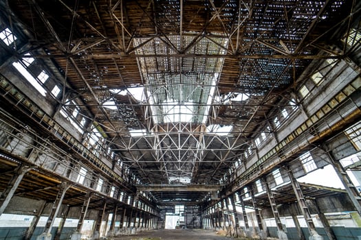 Light industrial interior of an old building with damaged ceiling and walls. Abandoned architecture of big broken warehouse inside, ruins and demolition concept. photo