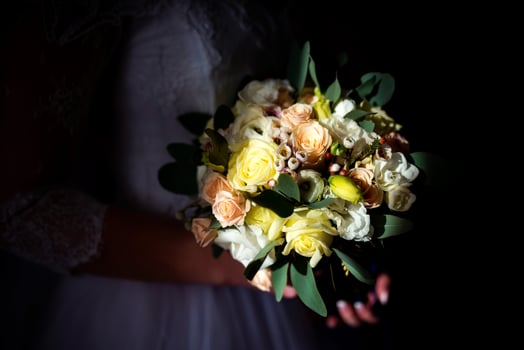 Wedding bouquet in bride's hands over the dark background. Beauty colored flowers for wedding in bride's hands. Close-up photo
