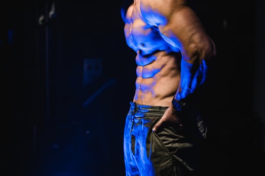 Brutal strong athletic men pumping up muscles. Workout and bodybuilding concept. Black and blue light background. Handsome man with naked torso. Fitness model is posing. photo