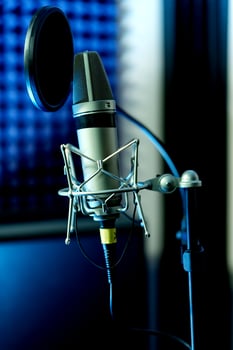 Close up studio condenser microphone with pop filter and anti-vibration mount live recording with color lights background. Side view photo