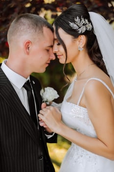 A young bride and groom tenderly embrace in the rays of the autumn sun. Tender and beautiful young girl bride. A man kisses his beloved. Against the background of a beautiful garden photo