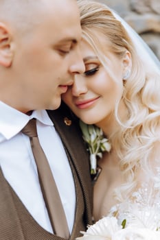 cute and stylish newlyweds are hugging and smiling against the background of autumn nature in a beautiful garden. An incredibly beautiful young bride kisses her lover photo