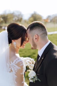 A young bride and groom tenderly embrace in the rays of the autumn sun. Tender and beautiful young girl bride. A man kisses his beloved. Against the background of a beautiful garden photo
