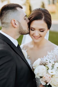 A young bride and groom tenderly embrace in the rays of the autumn sun. Tender and beautiful young girl bride. A man kisses his beloved. Against the background of a beautiful garden photo