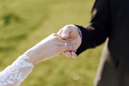 The groom kisses the bride's hand. Wedding photo of a couple in love. A young and handsome man kissing his wife's hand with a gold ring, proposing.