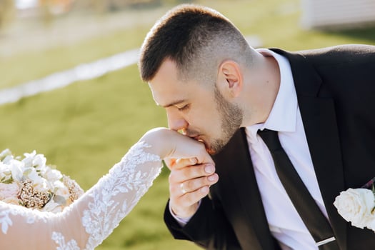 The groom kisses the bride's hand. Wedding photo of a couple in love. A young and handsome man kissing his wife's hand with a gold ring, proposing.
