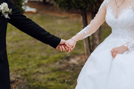 The groom kisses the bride's hand. Wedding photo of a couple in love. A young and handsome man kissing his wife's hand with a gold ring, proposing.