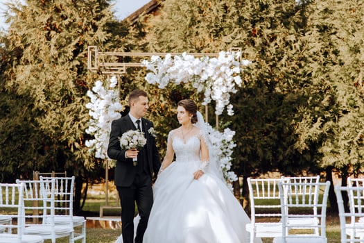 A wedding couple is walking in nature on an autumn day. Happy young bride and elegant groom holding hands. A stylish couple of newlyweds on their wedding day. photo