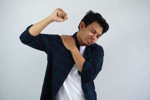young asian man touching his right shoulder with pain expression isolated on white background. photo