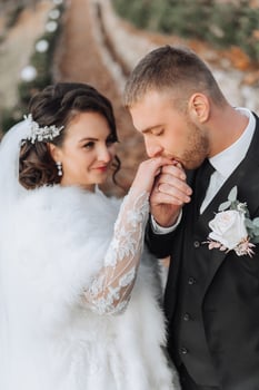 The groom kisses the bride's hand. Wedding photo of a couple in love. A young and handsome man kissing his wife's hand with a gold ring, proposing.