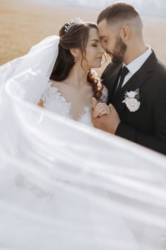A young bride and groom tenderly embrace in the rays of the autumn sun. Tender and beautiful young girl bride. A man kisses his beloved. Against the background of a beautiful garden photo