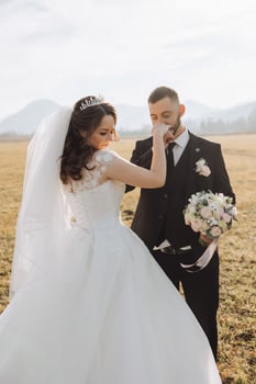 The groom kisses the bride's hand. Wedding photo of a couple in love. A young and handsome man kissing his wife's hand with a gold ring, proposing.