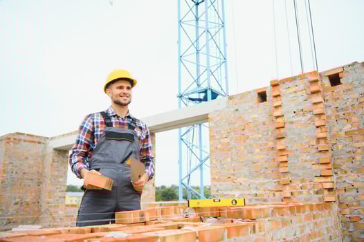 Construction worker man in work clothes and a construction helmet. Portrait of positive male builder in hardhat working at construction site. photo